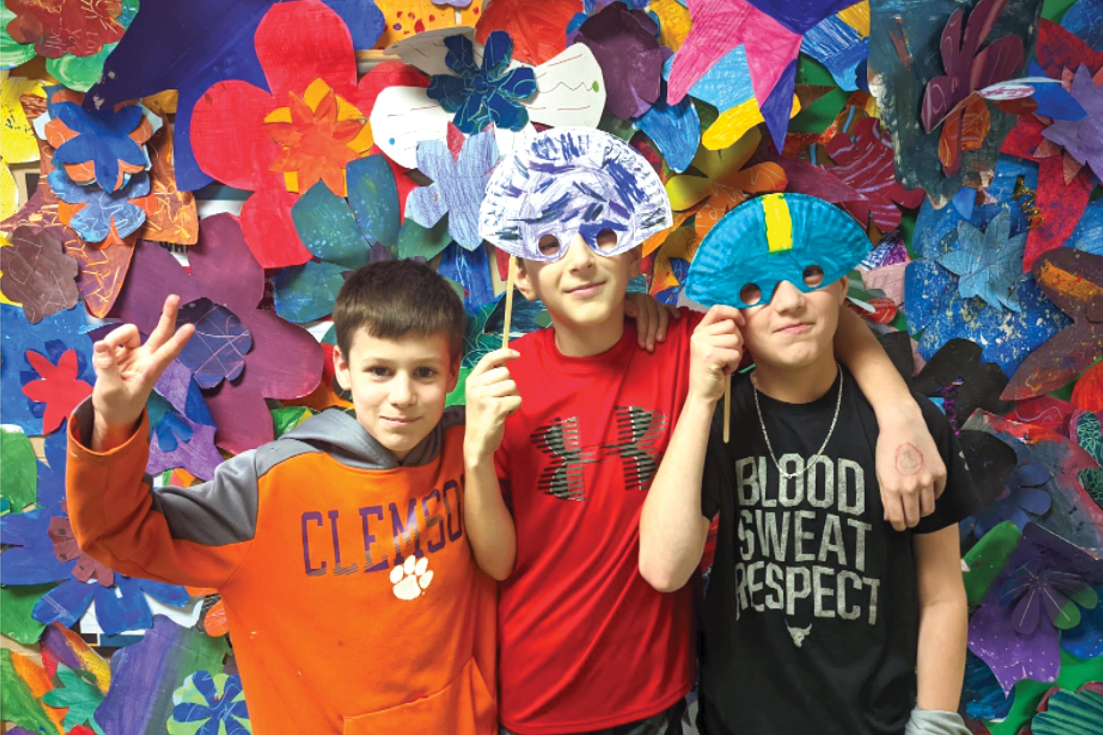 4th graders Walter Ledwich, Antonio Caruso and Colton Tirabassi in front of the flower wall