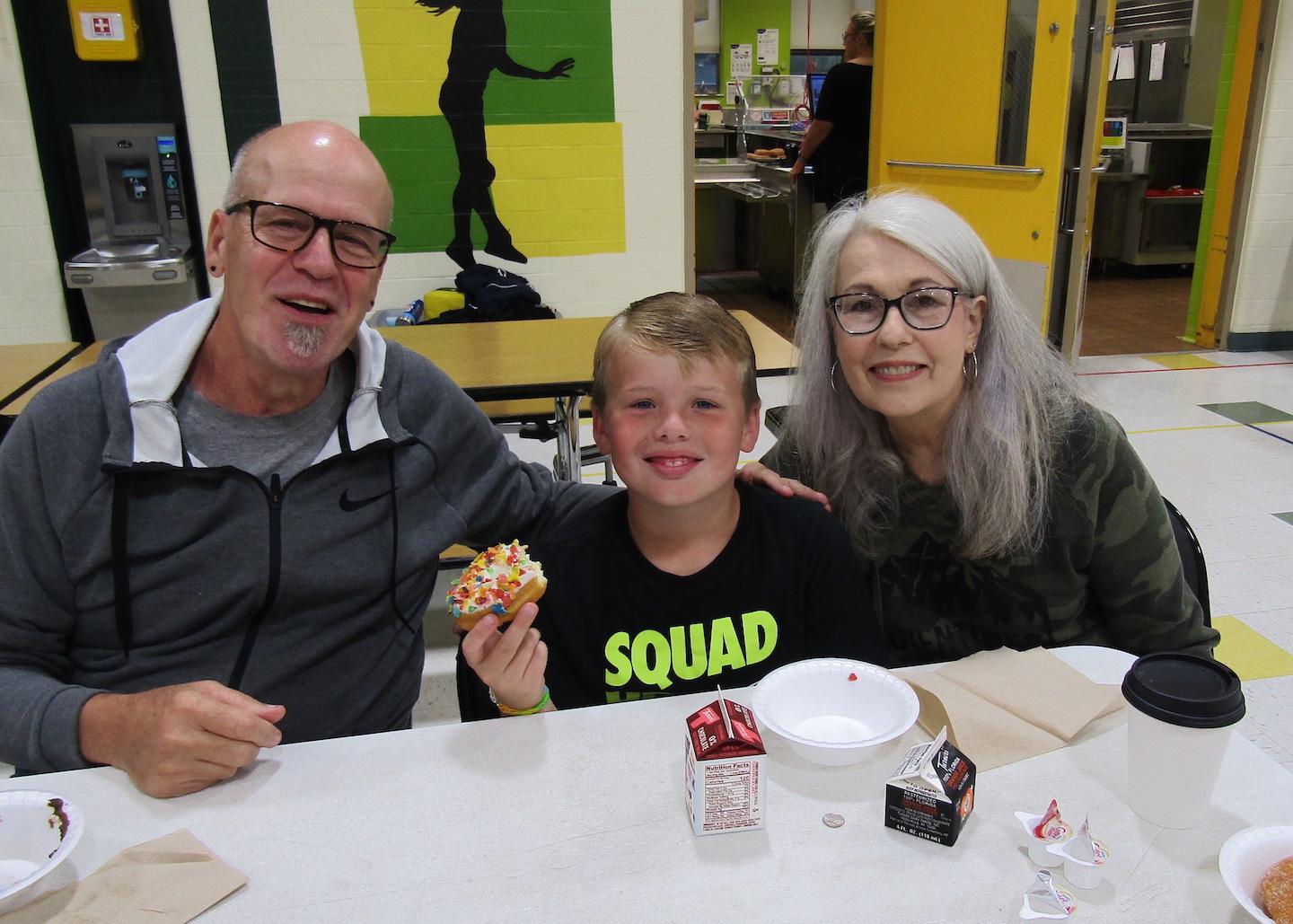 Third-grader Matthew Evangeliste enjoys a donut with his grandparents 