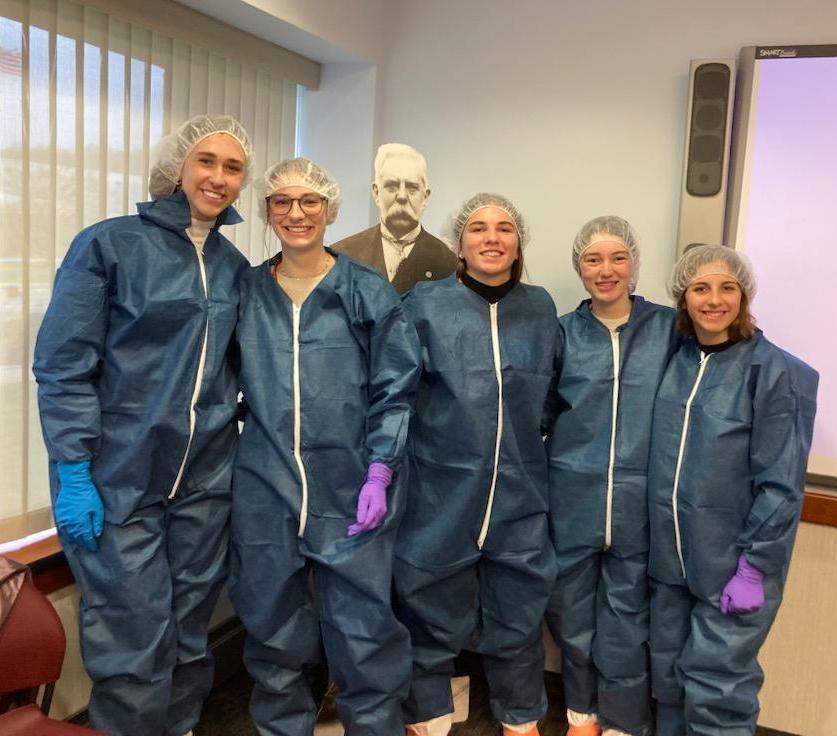 Posing (with George Westinghouse in the background) are Ella Dindak, Sophia Green, Mackenzie Keenan, Megan McCracken, and Lauren Burkley dressed in protective clothing and ready for nuclear work