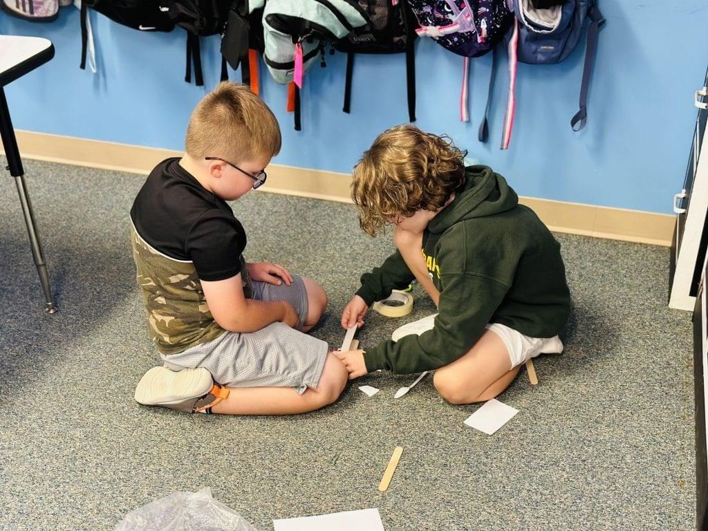 2nd-graders Logan Kostyak and Camden Schwer work as a team to build their paddles