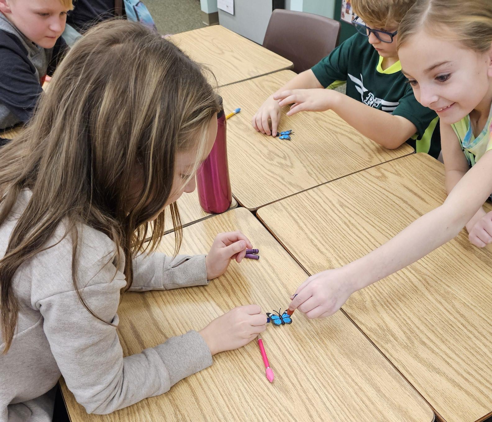 Quinn McIntosh and Natalia Tommasino use a magnet to move a metal butterfly 