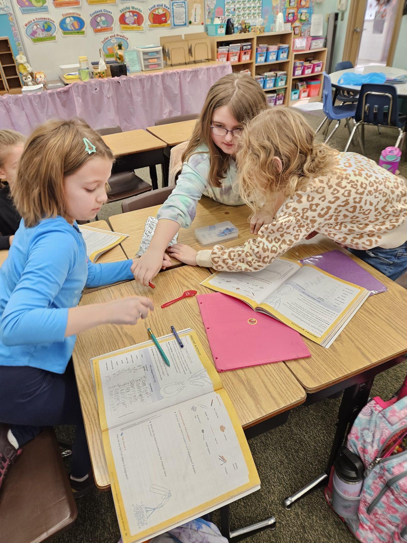 Mazzie Muller, Mia Myers, and Fallyn Houy test different objects to see if they are magnetic